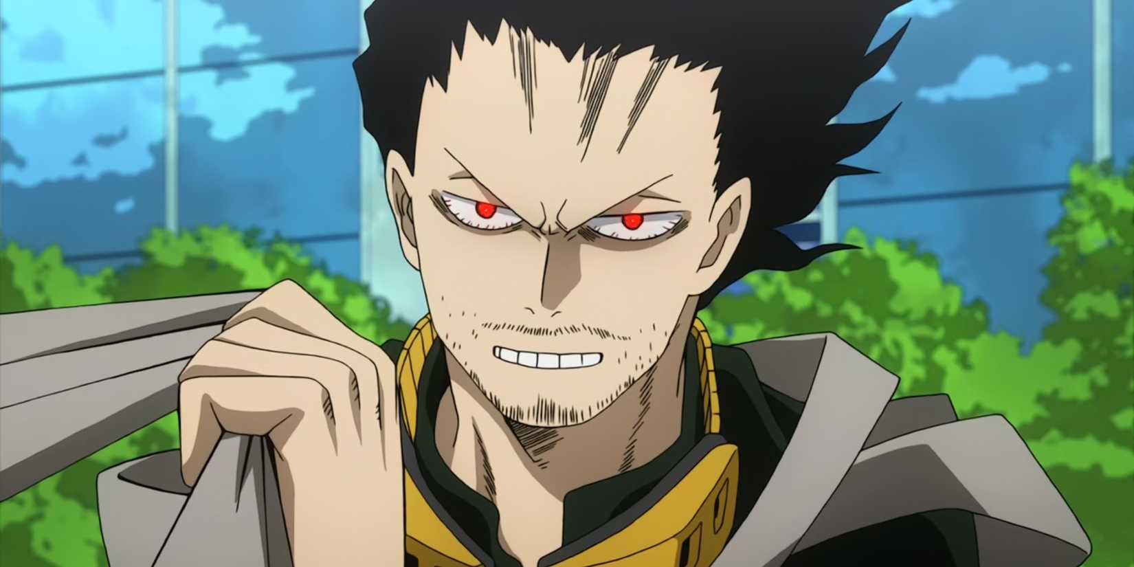 Shota Aizawa montre les dents tandis que ses yeux brillent de rouge et il tient le ruban de son costume.