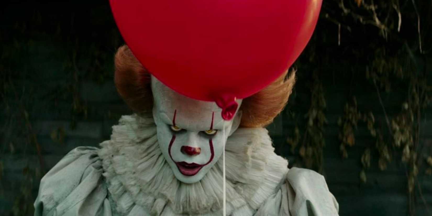 Bill Skarsgard as Pennywise the Clown holds a red balloon in Stephen King's IT 2017