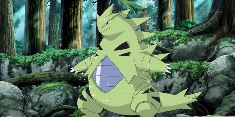 A Tyranitar sparkling in the forest in the Pokémon anime.