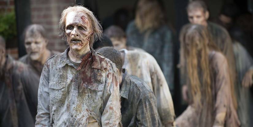 A walker in the crowd standing at attention in a scene from The Walking Dead.