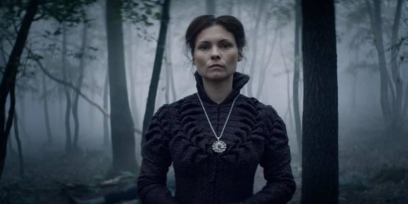 Tissaia wearing a medallion with a forest background