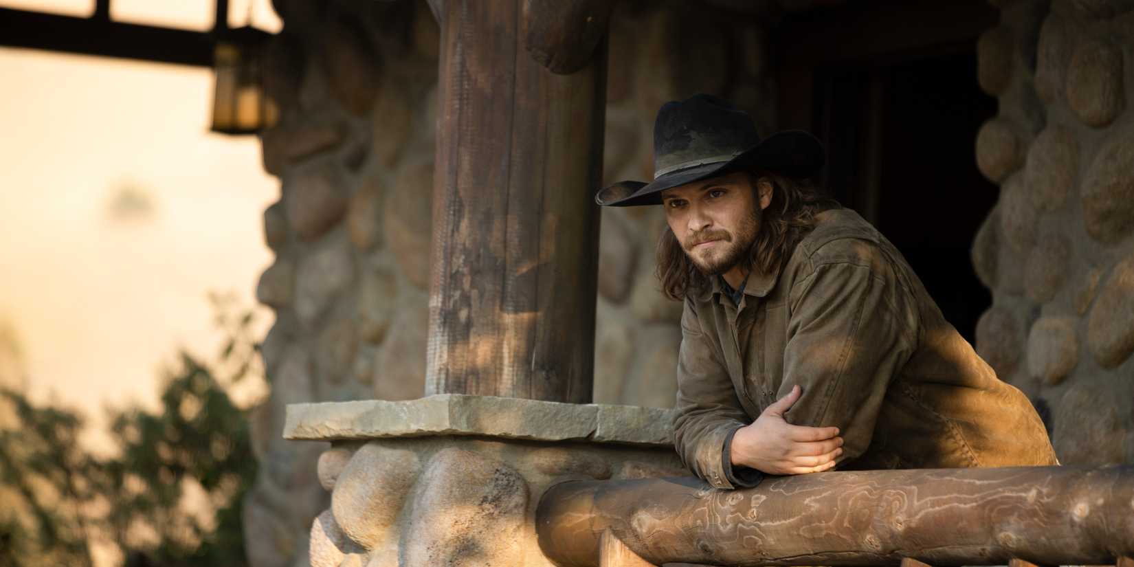 Kayce leans on a porch railing of the ranch in Yellowstone.