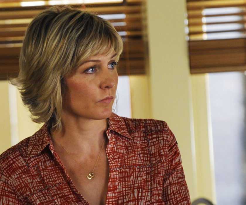 Amy Carlson as Linda Reagan standing in front of open window blinds in Blue Bloods.
