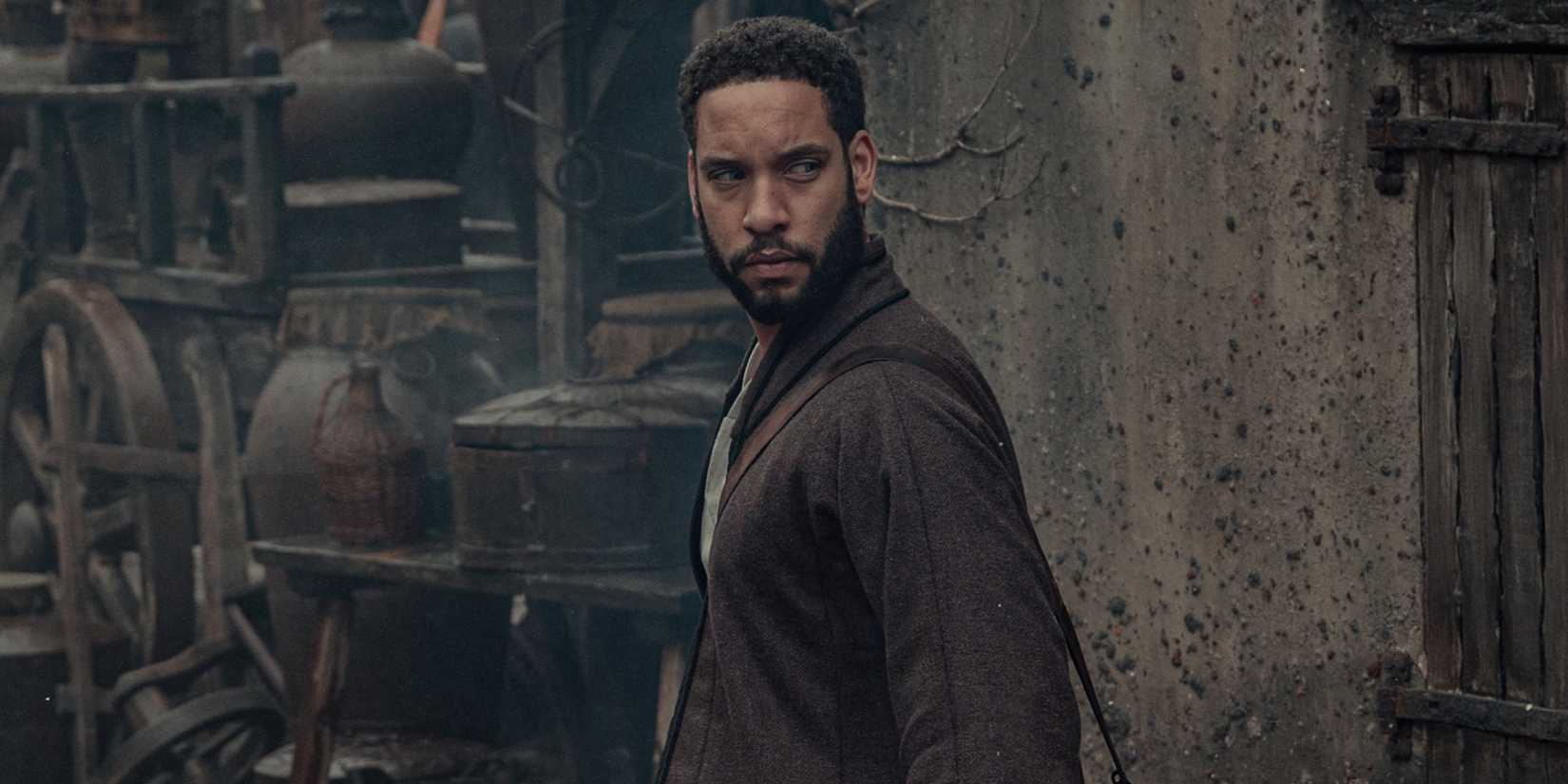 Istredd looks behind him while standing in a street