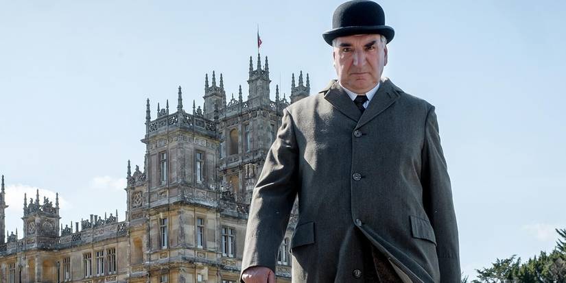 Mr Carson walks in front of a building in Downton Abbey.