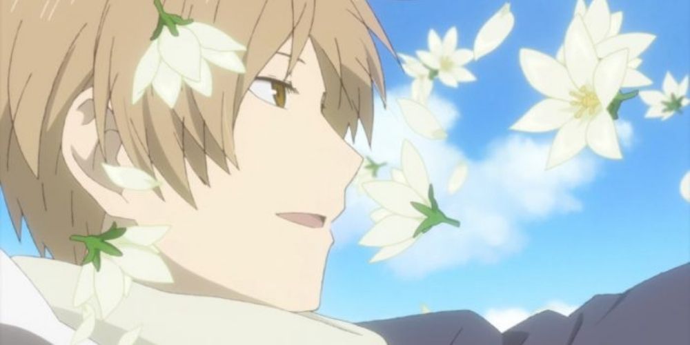 Natsume smiling with white flowers falling around him in Natsume's Book of Friends.
