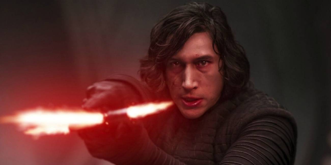 Adam Driver as Kylo Ren holds his lightsaber sideways in the Star Wars sequel trilogy.