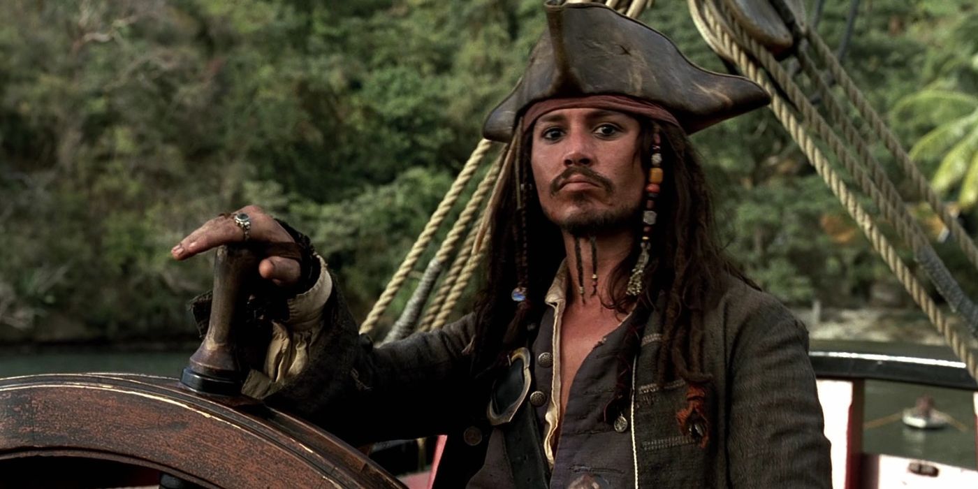 Jack Sparrow (Johnny Depp) está com a mão no leme de um navio em Piratas do Caribe: A Maldição do Pérola Negra.