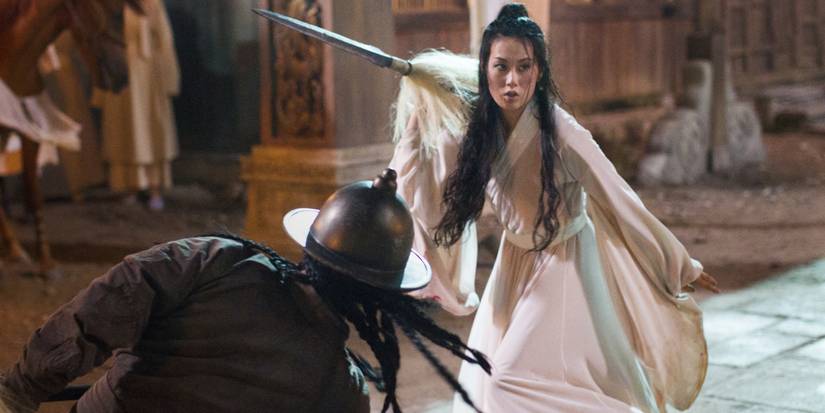 A woman wearing white and carrying a weapon fights off enemies in Netflix's Marco Polo.