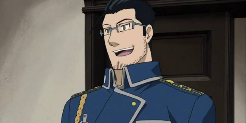 Maes Hughes de Fullmetal Alchemist : Brotherhood parle joyeusement dans une pièce.