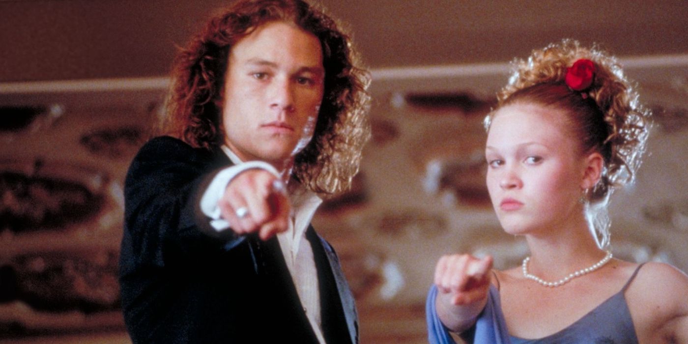 Patrick (Heath Ledger) e Kat (Julia Stiles) vestidos com um vestido e terno apontando para a tela em !0 Things I Hate About You