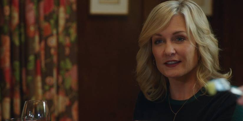 Amy Carlson as Blue Blood's Linda Reagan smiling in front of flowered drapes.