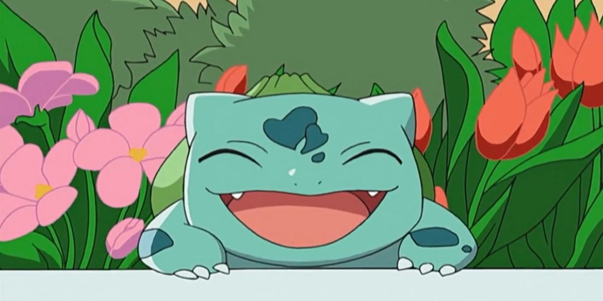 Bulbasaur sorrindo em um campo de flores no anime Pokémon.