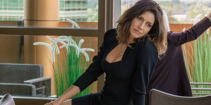 Sarah Atwood, played by Dawn Olivieri, wearing all black and leaning on a desk in Yellowstone