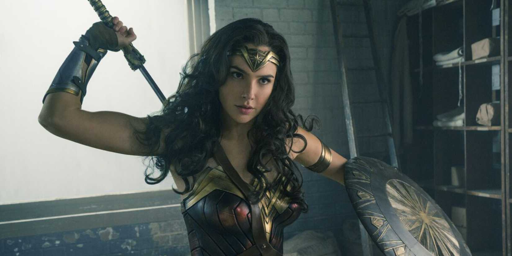Gal Gadot as Wonder Woman draws her sword while holding a shield in the 2017 movie Wonder Woman.