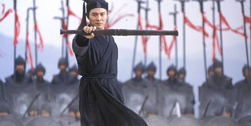Jet Li's character is holding a weapon out in front of himself while an army stands behind him in Hero.
