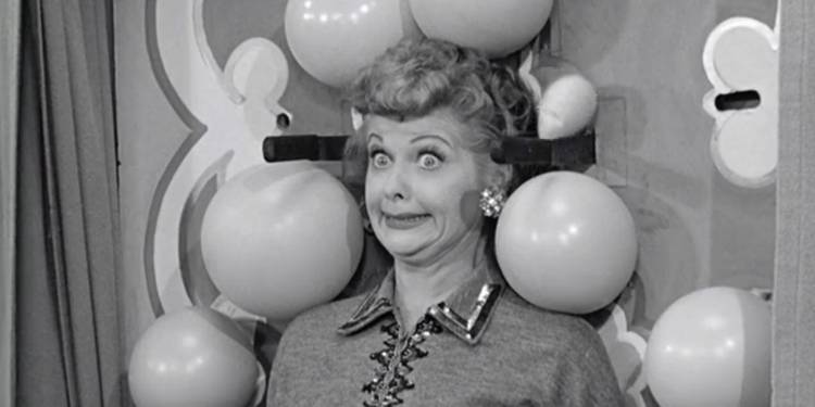 Lucy gives a terrified, wide-eyed smile while participating in a knife-throwing act in I Love Lucy, Lucy Tells The Truth.