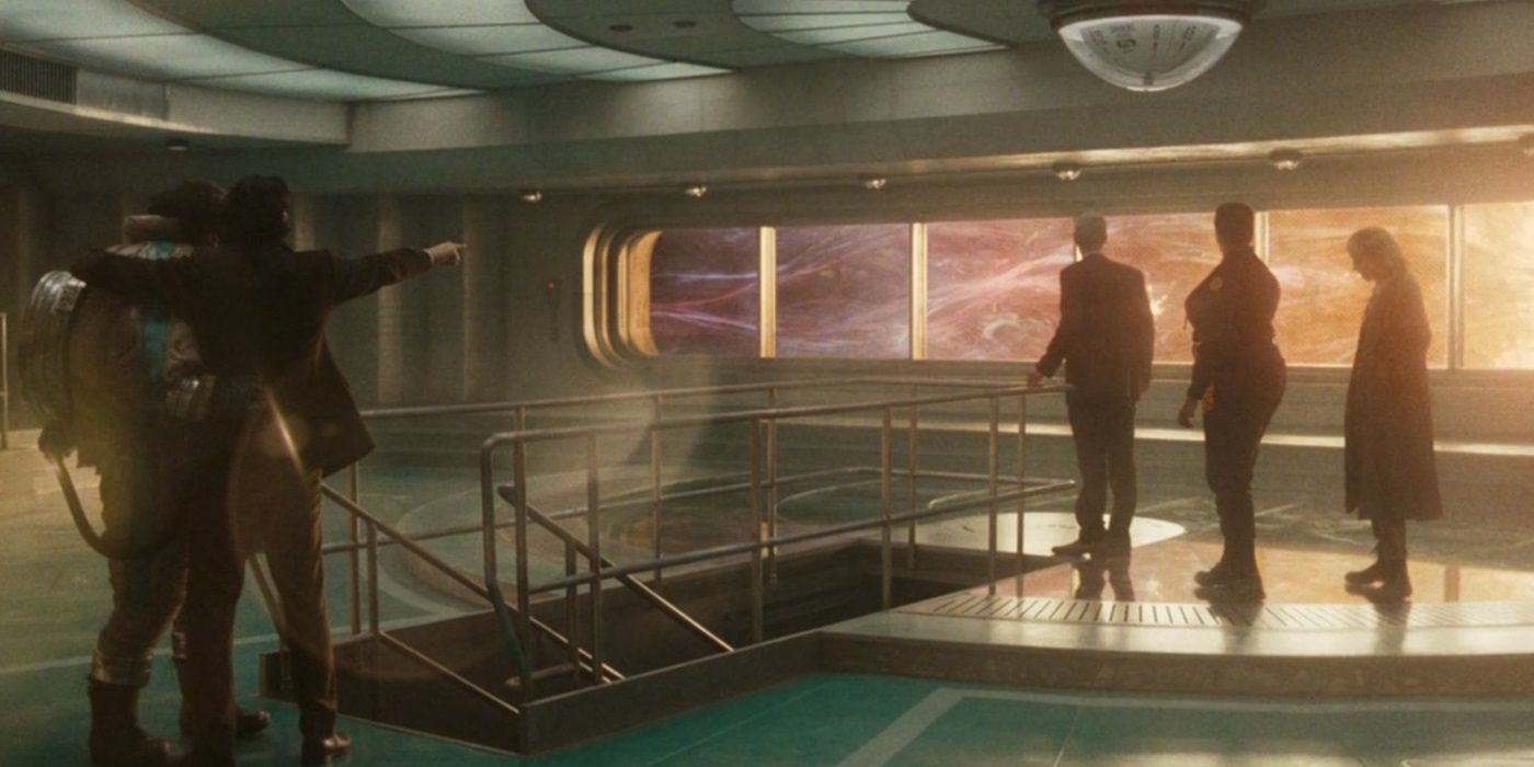 Loki com o braço em volta de Victor Timely, vestindo o traje espacial, na sala de observação da TVA com Sylvie, Hunter B-15 e Mobius em primeiro plano enquanto o Temporal Loom brilha