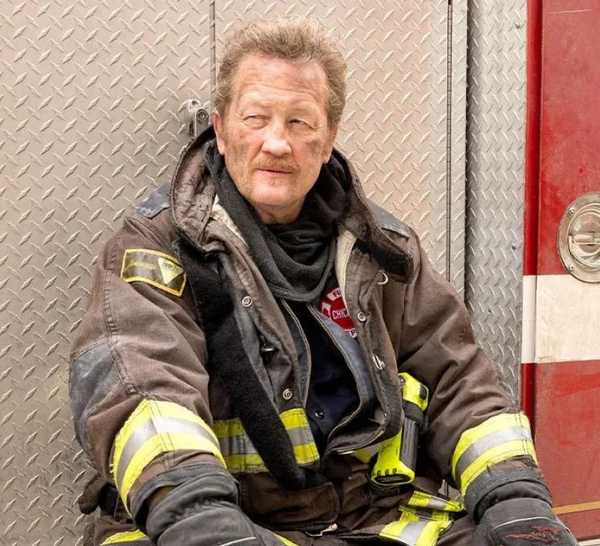 Christian Stolte leans against a fire truck as Randall 'Mouch' McHolland on Chicago Fire