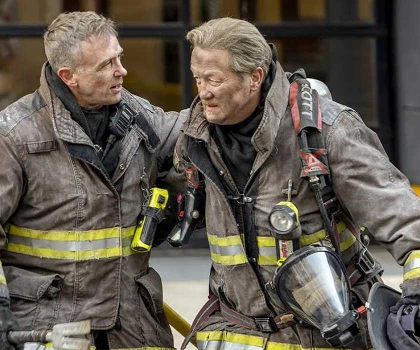 David Eigenberg as Christopher Herrmann helps Christian Stolte as Randall 'Mouch' McHolland out of a building on Chicago Fire