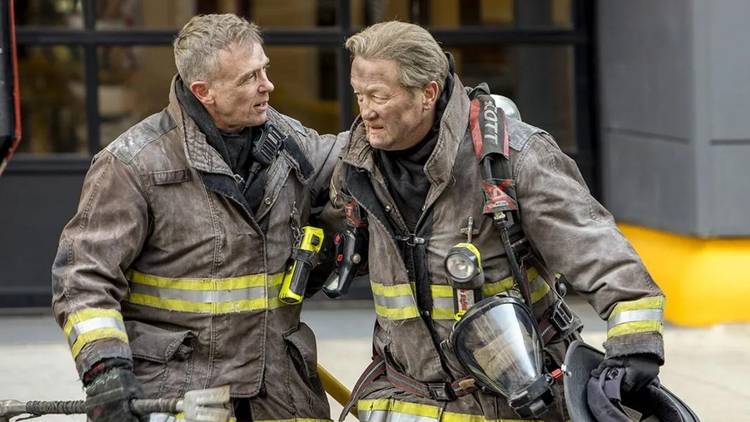 David Eigenberg as Christopher Herrmann helps Christian Stolte as Randall 'Mouch' McHolland out of a building on Chicago Fire