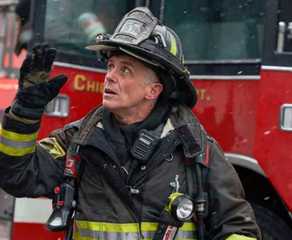 David Eigenberg looks up at a building as Christopher Herrmann on Chicago Fire
