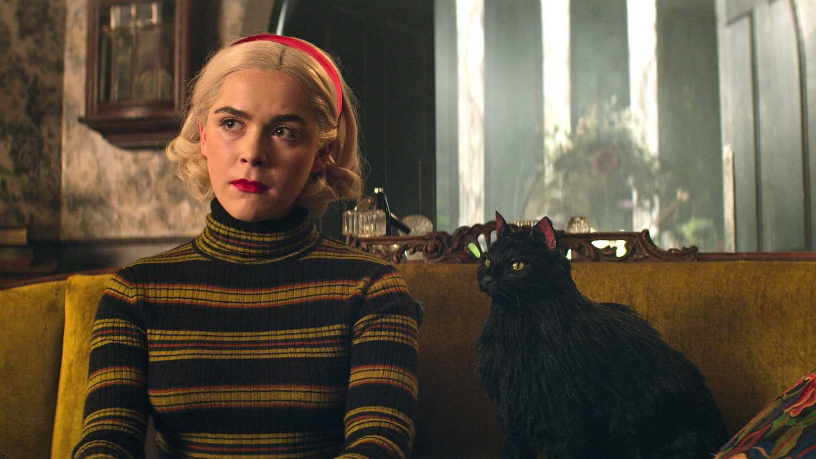 Sabrina Spellman, played by Kiernan Shipka, and a black cat in Chilling Adventures of Sabrina