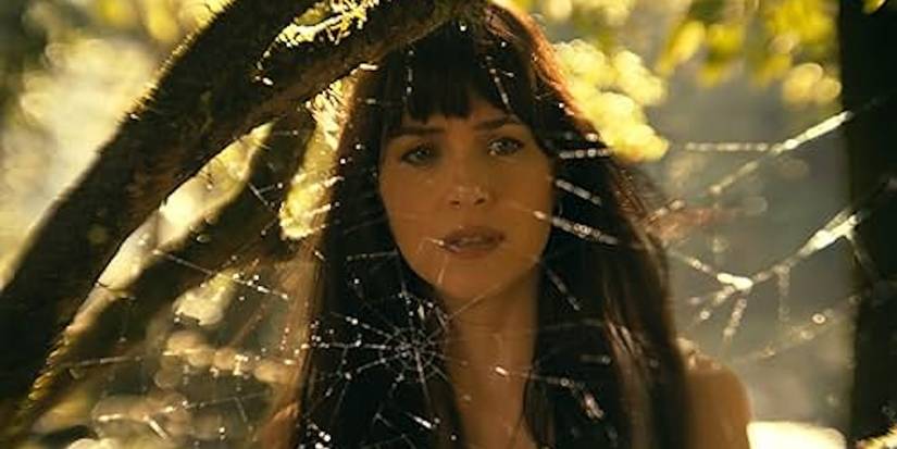 Dakota Johnson as Cassandra Webb thoughtfully examines a spiderweb in the Amazon. 
