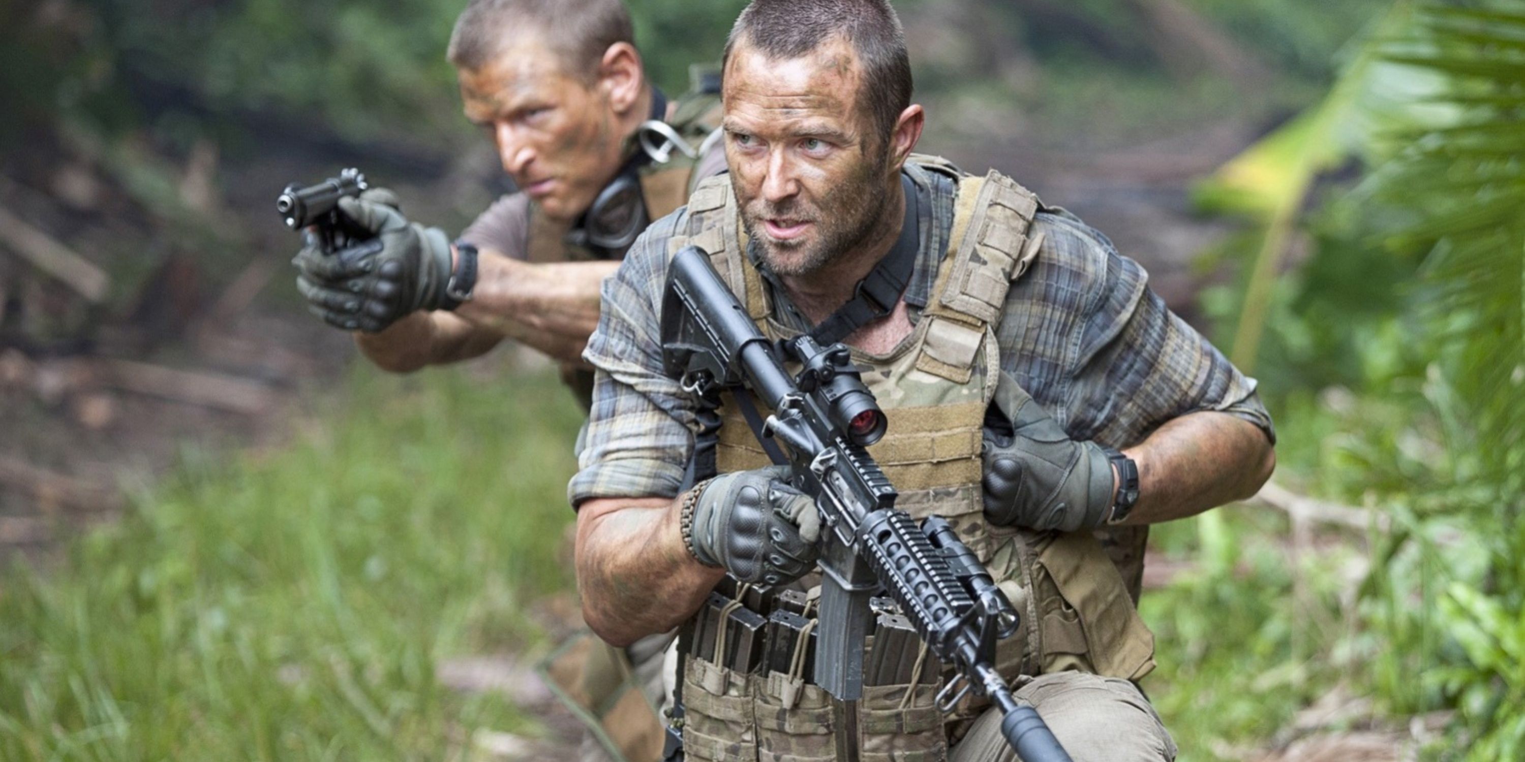 Scott e Stonebridge avançam por uma selva segurando armas em Strike Back