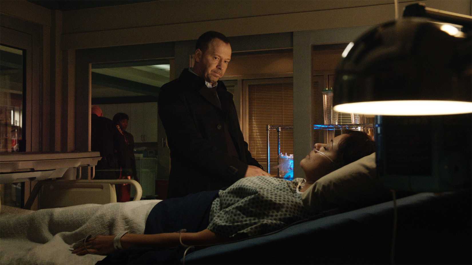 Danny Reagan stands by a hospital bed with Baez in it in Blue Bloods.