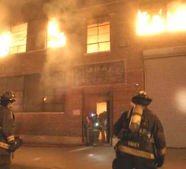 Firefighters standing outside of a burning building in Chicago Fire episode "Deathtrap"
