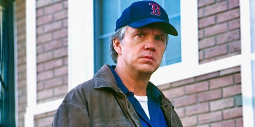 Tim Robbins as Dave stands outside a house wearing a Boston Red Sox cap in Mystic River.