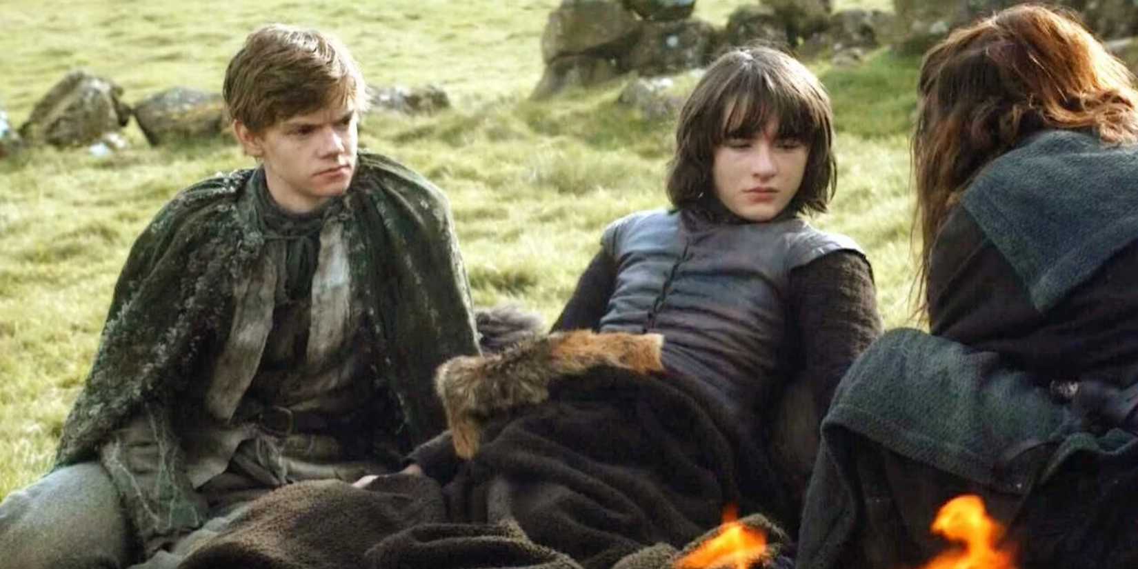 Jojen Reed and Bran Stark sit by the camp fire in Game of Thrones.