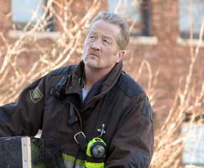 Mouch (actor Christian Stolte) in firefighter gear on top of the truck in Chicago Fire