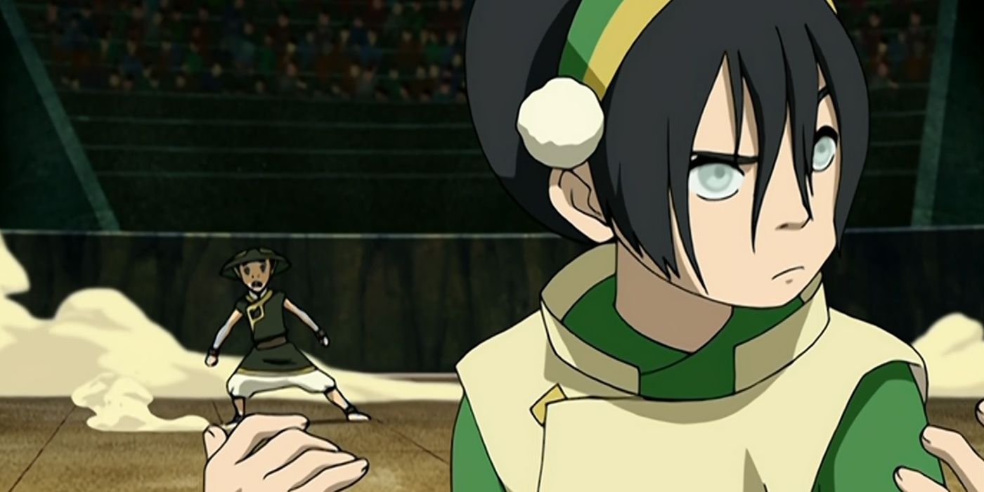 Toph olha ao redor na arena enquanto Aang está atrás dela.