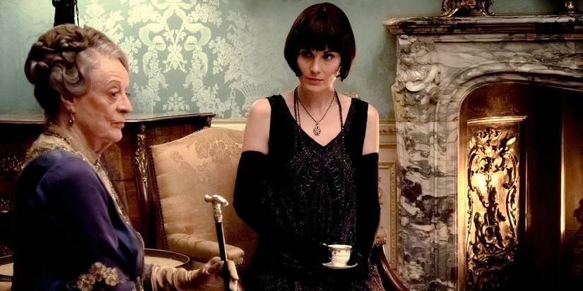 Violet and Lady Mary seated in front of a fireplace in the first Downton Abbey movie
