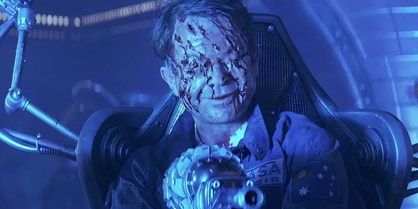 A scary man with damage to his face holds a pistol in event horizon