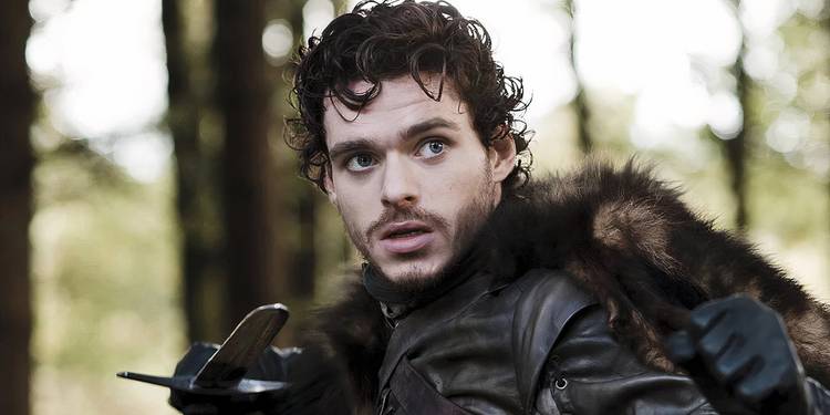 Richard Madden as Robb Stark pointing his sword at someone in Game of Thrones