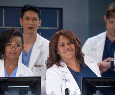 Griffith, Kwan, Bailey, and Link stand together in their white coats in front of a television screen on Grey's Anatomy
