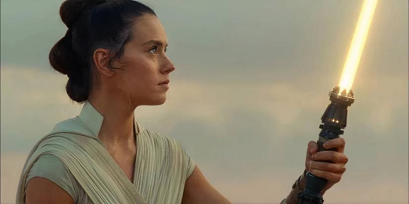 Daisy Ridley as Rey Skywalker wielding her new yellow lightsaber on Tatooine at the end of The Rise of Skywalker.