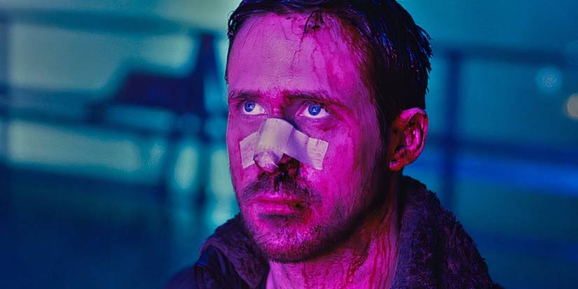K stands in a neon colored area with a bandage on his nose in Blade Runner 2049