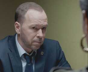 Danny Reagan, played by Donnie Wahlberg, wearing a suit and sitting across from a witness in Blue Bloods.