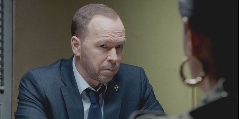 Danny Reagan, played by Donnie Wahlberg, wearing a suit and sitting across from a witness in Blue Bloods.