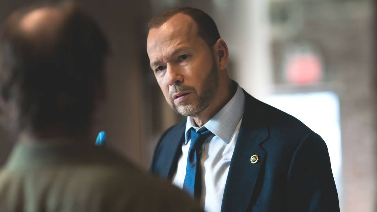 Danny Reagan, played by actor Donnie Wahlberg, wearing a suit speaking to a witness in Blue Bloods