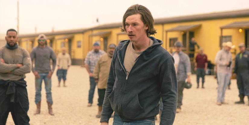 Cooper Norris, played by Jacob Lofland, stands out of breath while the camp surrounds him in Landman