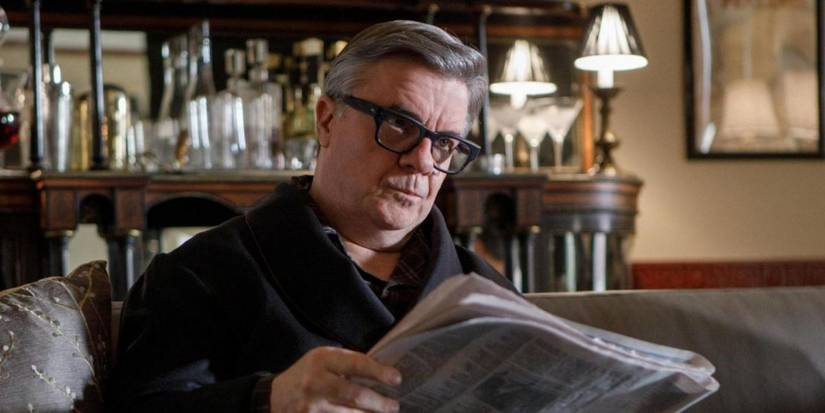 Teddy (Nathan Lane) reads a newspaper in only murders in the building