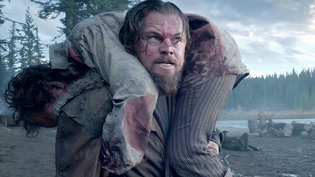 Hugh Glass carrega um aliado ferido após um ataque intenso em The Revenant