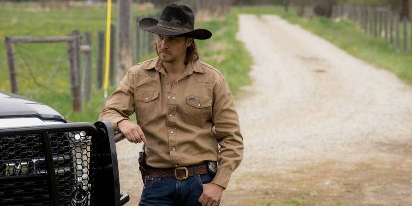 Kayce Dutton, played by Luke Grimes, leans on truck wearing tan shirt and cowboy hat in Yellowstone