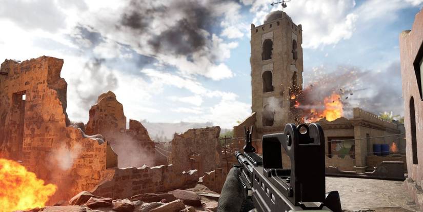 A character in Insurgency: Sandstorm is standing in front of a town that is getting bombed.