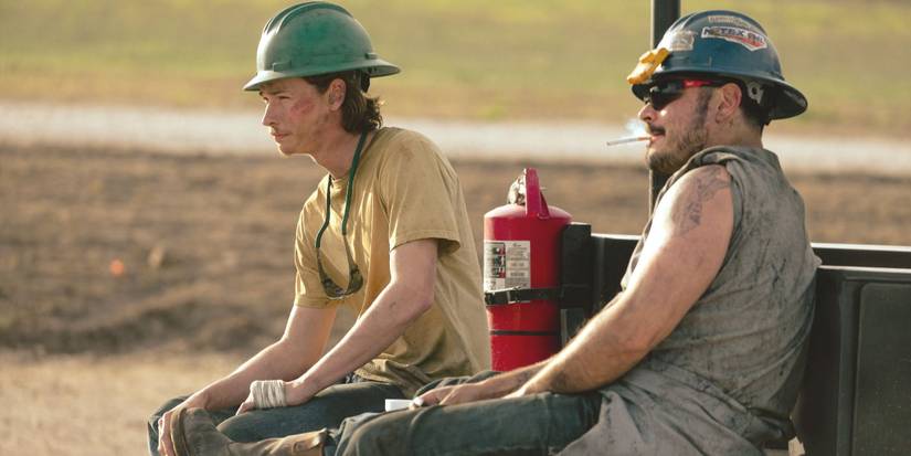 Cooper Norris sits on a truck's tailgate next to Manuel, both of them covered in oil, in Landman